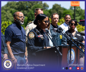 Chief Davis speaks at an outdoor press conference, standing at a podium with multiple news microphones. Behind him are several law enforcement and public safety officials, including individuals in FBI and emergency services attire. Trees and greenery are visible in the background. A Memphis Police Department seal and recruitment website appear at the bottom of the image.