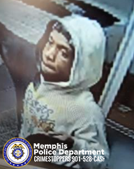 "An individual wearing a light-colored hooded sweatshirt with a graphic design on the front is standing indoors near a counter or display case. The background shows portions of shelves or surfaces with various items. The person is positioned slightly angled, with the hood up. In the lower-left corner, there is a Memphis Police Department CrimeStoppers badge and contact information."