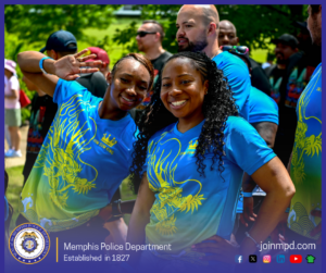 A group of people are standing outdoors at what appears to be a community or team event held in a park-like setting with green trees in the background. Several individuals in the foreground are wearing matching blue and yellow shirts featuring a stylized dragon graphic and text that reads “DJI SUM KING.” One individual is posing with an arm raised and palm facing outward, while another stands with hands on hips. Additional participants wearing similar shirts are visible behind them, along with a crowd of people in casual clothing further in the background. At the bottom of the image, a banner displays the Memphis Police Department seal, the text “Memphis Police Department – Established in 1827,” the website joinmpd.com, and various social media icons.