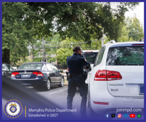 A uniformed Memphis Police Department officer stands beside a white SUV during what appears to be a traffic stop on a tree‑lined street. Several parked and passing cars are visible in the background. The lower part of the image includes the Memphis Police Department seal, the text “Memphis Police Department – Established in 1827,” and the URL joinmpd.com along with various social media icons.