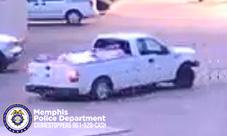 A white pickup truck is driving through an intersection or parking‑lot-style roadway, angled slightly as if turning. The truck’s bed appears to contain loose material covered with a light-colored sheet or tarp. Another vehicle is partially visible in the background near the upper left corner. The scene is captured in low‑light or early‑evening conditions, giving the image a slightly bluish tone. In the lower left corner, a Memphis Police Department badge graphic appears along with text that reads “Memphis Police Department CRIMESTOPPERS 901‑528‑CASH.”