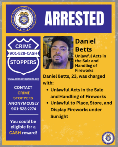  A poster-style graphic with a gold and blue color scheme. At the top is the Memphis Police Department seal next to a large blue banner displaying the word “ARRESTED” in bold white letters. On the left side, a blue shield-shaped Crime Stoppers graphic shows the phone number 901‑528‑CASH, the website crimestopmem.org, and information about contacting Crime Stoppers anonymously and qualifying for a cash reward. In the center is a rectangular photo of a person’s upper body. To the right of the photo, text reads “Daniel Betts” followed by “Unlawful Acts in the Sale and Handling of Fireworks.” Below that, additional text states: “Daniel Betts, 23, was charged with:” followed by two bullet points describing charges involving unlawful acts in the sale and handling of fireworks, and unlawful placement, storage, and display of fireworks under sunlight. The bottom-right corner includes a small Memphis Police Department seal.