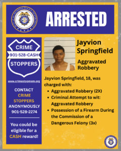 A Memphis Police Department arrest flyer with a blue and yellow color scheme. The top section features the department seal on the left and the word “ARRESTED” in large white letters on a blue background. The left side of the flyer displays a “Crime Stoppers” badge icon with the number 901‑528‑CASH, the website crimestopmem.org, and information about contacting Crime Stoppers anonymously for a possible cash reward. In the center is a booking photo area showing an individual standing in front of height measurement lines. On the right, text reads: “Jayvion Springfield – Aggravated Robbery.” Below, additional text states that Jayvion Springfield, age 18, was charged with aggravated robbery (2 counts), criminal attempt to commit aggravated robbery, and possession of a firearm during the commission of a dangerous felony (3 counts). The bottom corner includes the Memphis Police Department seal.