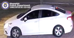 A nighttime surveillance-image showing a white four-door sedan stopped on a roadway. The vehicle’s front wheels are slightly turned, and the driver-side window is open. The lighting is bright around the car, but the interior is dark, making the occupants not clearly visible. In the upper-left corner of the image is the Memphis Police Department emblem and text that reads: “Memphis Police Department CRIMESTOPPERS 901-528-CASH.”